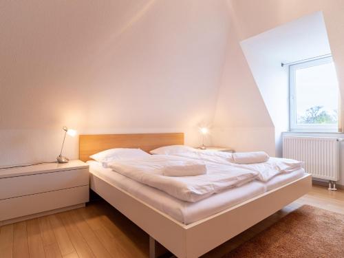 ein Schlafzimmer mit einem weißen Bett mit zwei Nachttischen und einem Fenster in der Unterkunft Grüne Straße FeWo G3 (DG links) in Prerow