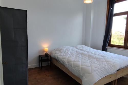 a bed in a bedroom with a lamp on a table at TOK TOK Ronchin Maison Proche toutes commodités Lille in Ronchin