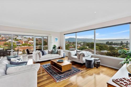a living room with white furniture and large windows at Seaview at Gerringong - 4pm check out if available in Gerringong
