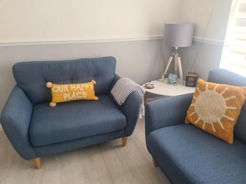 a living room with a blue chair and a pillow at Private 2 bedroom house close to the beach in Paignton