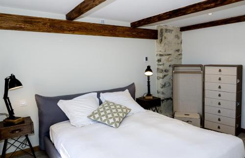 ein Schlafzimmer mit einem weißen Bett mit einem Kissen darauf in der Unterkunft Cottage - La Maison du Château - By DOMAINE RIBERACH in Bélesta