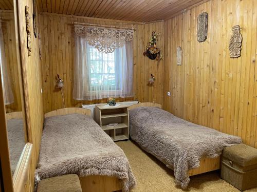 two beds in a room with wooden walls and a window at Grunok (Adults only) in Pilipets