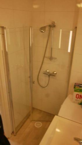 a bathroom with a shower with a toilet and a sink at Nyrenovert leilighet med gratis parkering in Leknes