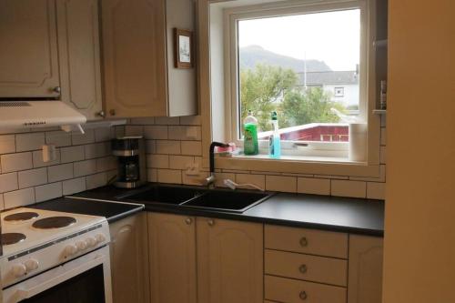 a kitchen with a sink and a window at Nyrenovert leilighet med gratis parkering in Leknes