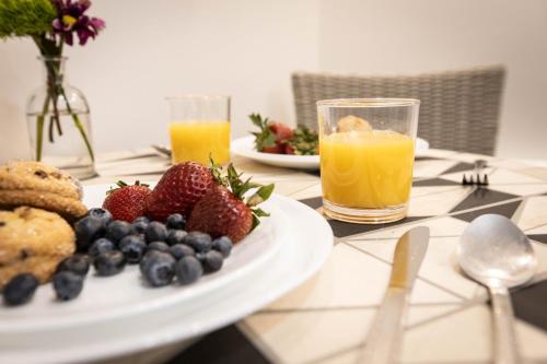 a plate of fruit on a table with orange juice at Ocean View Terrace in Hampton Bays