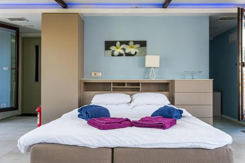 a large white bed with two purple towels on it at Joan Apartments & Spa in Skopje