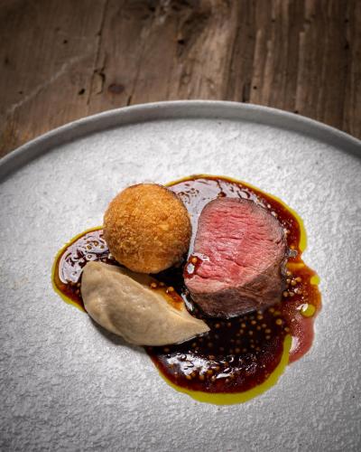 a piece of meat on a plate with sauce at Skåbu Fjellhotell in Skåbu