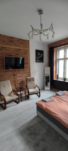 a bedroom with a bed and two chairs and a tv at LIBERation! in Olsztyn
