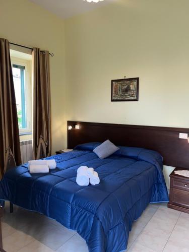 um quarto com 2 camas com lençóis azuis e toalhas em Agriturismo Le Grottelle em SantʼAgata sui Due Golfi