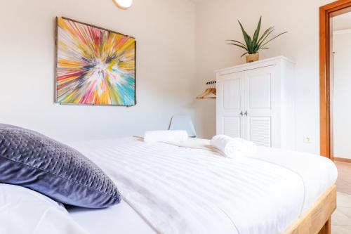 a bedroom with a white bed with a painting on the wall at 4 You Apartments in Mugeba