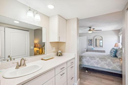 a bathroom with a sink and a bed with a mirror at Emerald Isle 604 in St Pete Beach