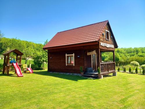 une petite maison avec une aire de jeux et un toboggan dans l'établissement Chatka Zuzia, à Polańczyk