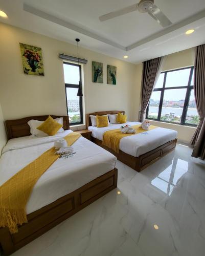 two beds in a room with windows at Romano Hotel in Kampot