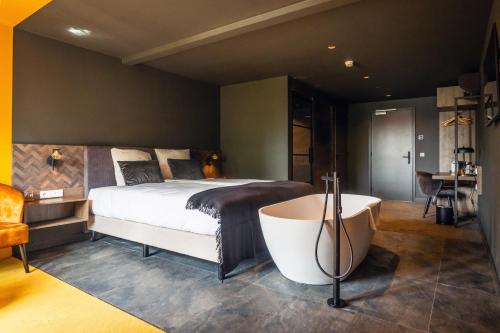 a bedroom with a large bed and a bath tub at Prins Hendrik Texel in Oost
