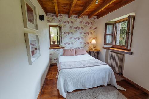 ein Schlafzimmer mit einem Bett und zwei Fenstern in der Unterkunft Finca La Casería LA CASA in Cangas de Onís
