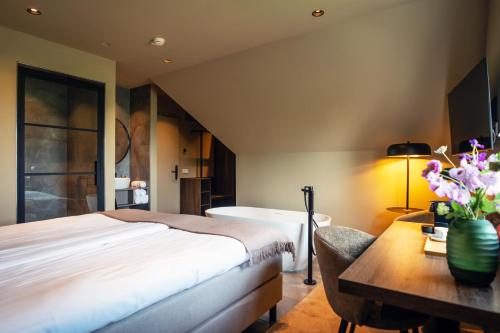 a bedroom with a bed and a desk with a table at Prins Hendrik Texel in Oost