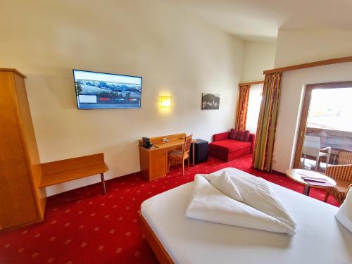 a hotel room with a bed and a desk and a television at Das Alpin - Hotel Garni Guesthouse in Scheffau am Wilden Kaiser
