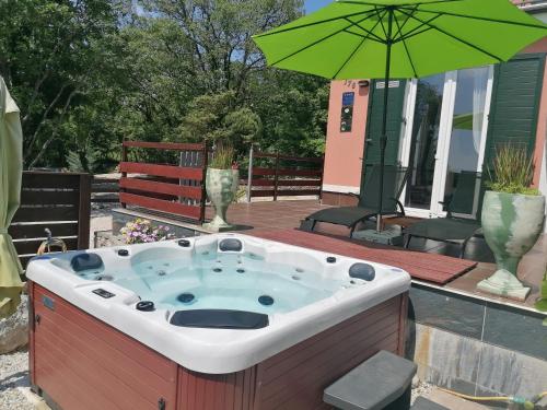 a hot tub on a patio with a green umbrella at The Forest House Krk 1 in Kras