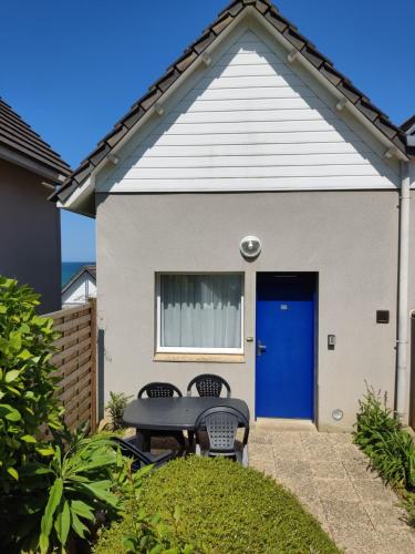 une maison avec une porte bleue et deux chaises dans l'établissement Maison VUE MER 50m PLAGE de TRESTEL GR34 entre Perros Guirec côte de granit rose et l'île de Bréhat, à Trévou-Tréguignec