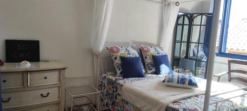 a bedroom with a bed with blue pillows and a window at Parfumu Di Celu in Corte