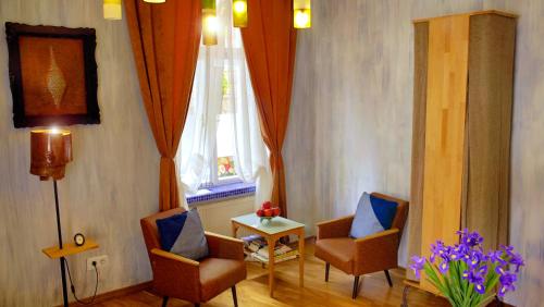 een woonkamer met 2 stoelen, een tafel en een raam bij Colors Apartments - Ochre in Lviv