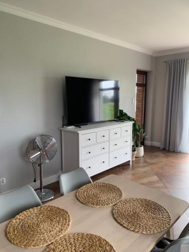 a living room with a table with chairs and a tv at Dom nad jeziorem in Jeziorany