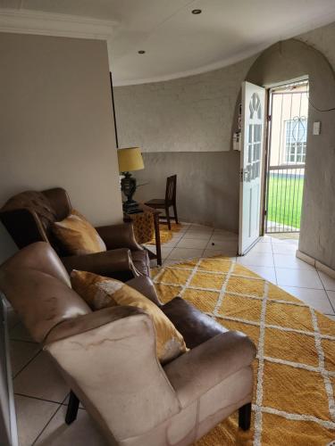 a living room with a leather couch and a table at Chalet 1 bedroom in Boksburg