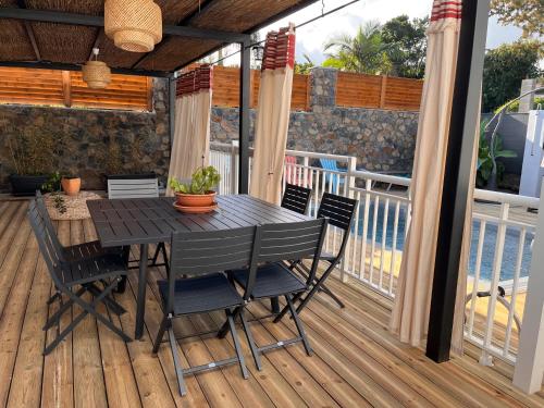 eine Holzterrasse mit einem Tisch und Stühlen darauf in der Unterkunft La Casita Créole villa avec piscine et jacuzzi in Saint-Pierre