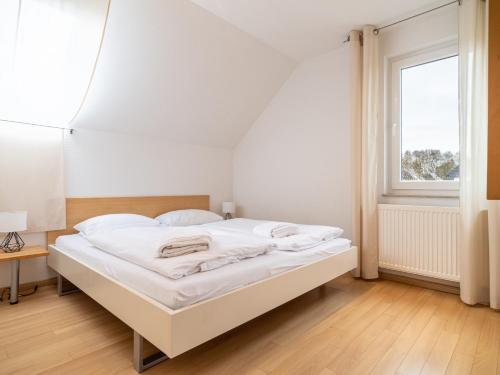 białe łóżko w pokoju z oknem w obiekcie Grüne Straße FeWo G8 (DG rechts) w Prerowie