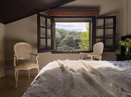 een slaapkamer met een bed en twee stoelen en een raam bij Casa Magnolia in Dosríus