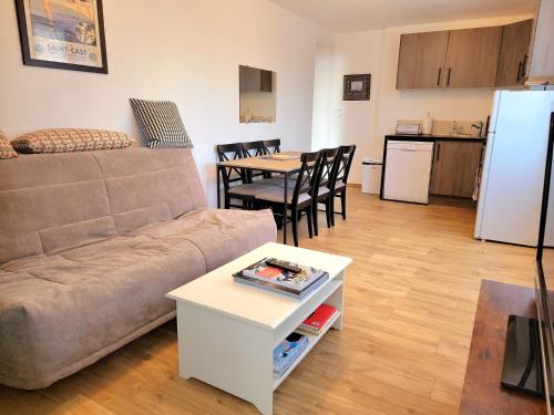 uma sala de estar com um sofá, uma mesa e uma cozinha em Appartement dans le bourg du Guildo - Saint-Cast em Saint-Cast-le-Guildo