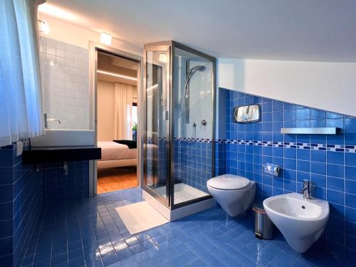 a blue tiled bathroom with a toilet and a shower at Villa Arianna Acireale in Acireale