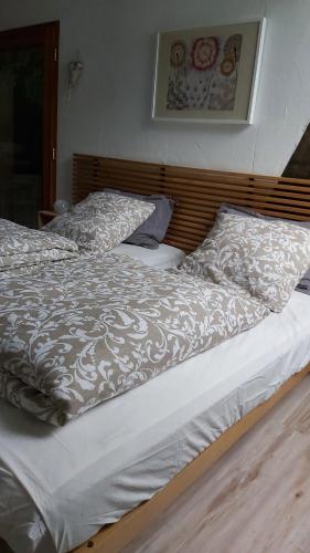 uma cama com um edredão branco e 2 almofadas em Herbes et collines em Winkel
