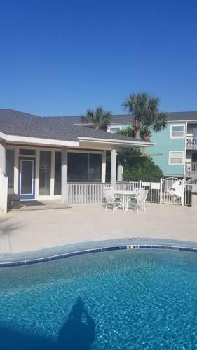 a house with a swimming pool in front of a house at Quiet 2 bedroom condo on Gulf with pool and pond in Pensacola Beach