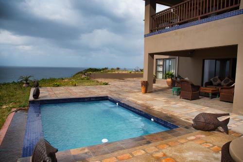 a swimming pool in front of a house with the ocean at Villa Castellos in Inhambane