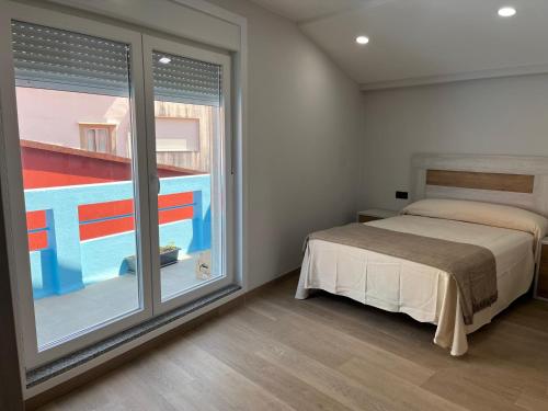 ein Schlafzimmer mit einem Bett und einem großen Fenster in der Unterkunft Apartamento puerto in A Guarda
