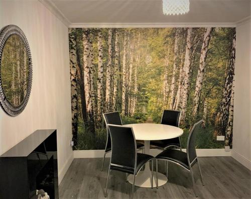 ein Esszimmer mit einem Tisch und Stühlen vor einem Baumbild in der Unterkunft Ann St Vacation Apartment Greenock United Kingdom in Greenock