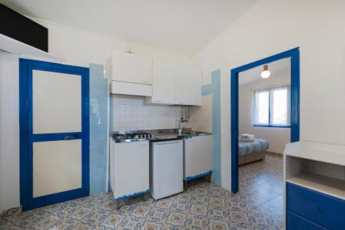 a kitchen with white cabinets and a blue door at Villaggio Residence Nettuno in Massa Lubrense