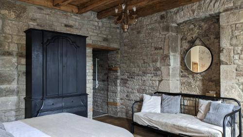 a bedroom with a bed and a couch in a stone wall at Manoir La Cerise in Fougerolles