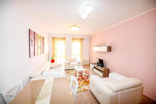 a living room with white furniture and a table at Happy stories' apartment in city centre in Shkodër