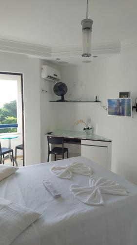 a white bedroom with a white bed and a table at Ondina Atlantic City in Salvador
