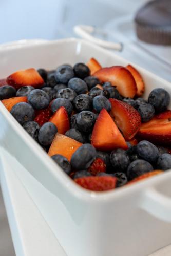 a white bowl filled with blueberries and fruit at Ocean View Terrace in Hampton Bays