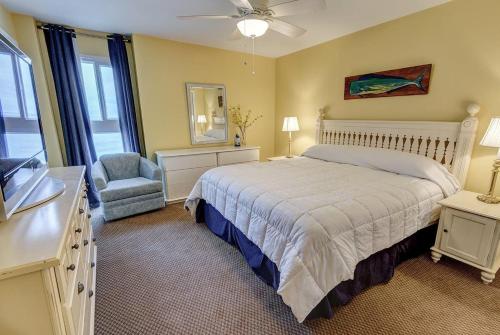 een slaapkamer met een bed, een stoel en een televisie bij Edgewater West 53 by ALBVR - This Beachfront Condo is Perfect for your next Family Getaway in Gulf Shores