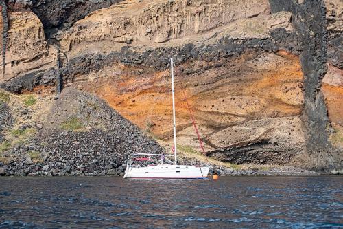 um barco sentado na água ao lado de uma montanha em Orpheus em Chora, Ios