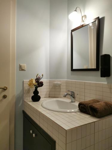 a bathroom sink with a mirror and a vase of flowers at Armonia Petra House in Kavála