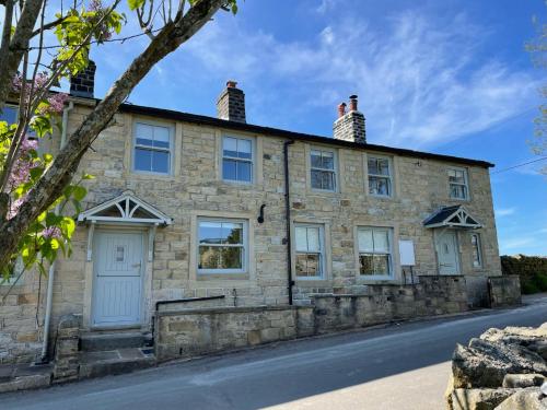 an old stone house on the side of a road at Swartha Cottages in Silsden