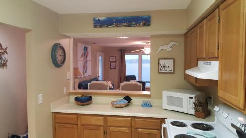 a kitchen with a sink and a microwave at Sea Oats E202 by ALBVR - Pet Friendly Direct Lagoon Front Renovated 2BR, 2BA Condo, Outdoor Pools, Pier, and Dedicated Beach Access in Gulf Shores