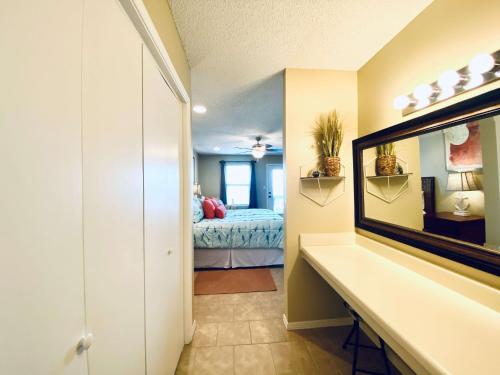 a bathroom with a mirror and a bed in a room at Sea Oats E202 by ALBVR - Pet Friendly Direct Lagoon Front Renovated 2BR, 2BA Condo, Outdoor Pools, Pier, and Dedicated Beach Access in Gulf Shores