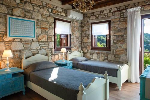 1 dormitorio con 2 camas y pared de piedra en 2 beautiful sea villas 17guests, en Damouchari