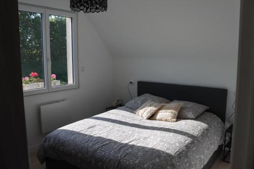 a bedroom with a bed with two pillows and a window at Entre terre et Mer in Saint-Lormel